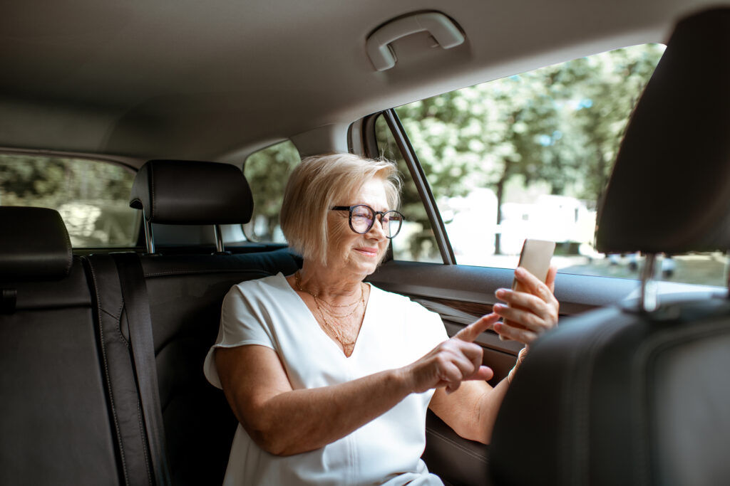 Senior woman with phone in the car
